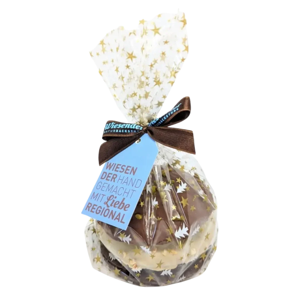 Mehrere Lebkuchen der Bäckerei Wiesender, eingewickelt in sternförmiges Zellophan, verschnürt mit einer braunen Schleife und einem blauen Anhänger mit der Aufschrift "Wiesender Hand gemacht mit Liebe regional".