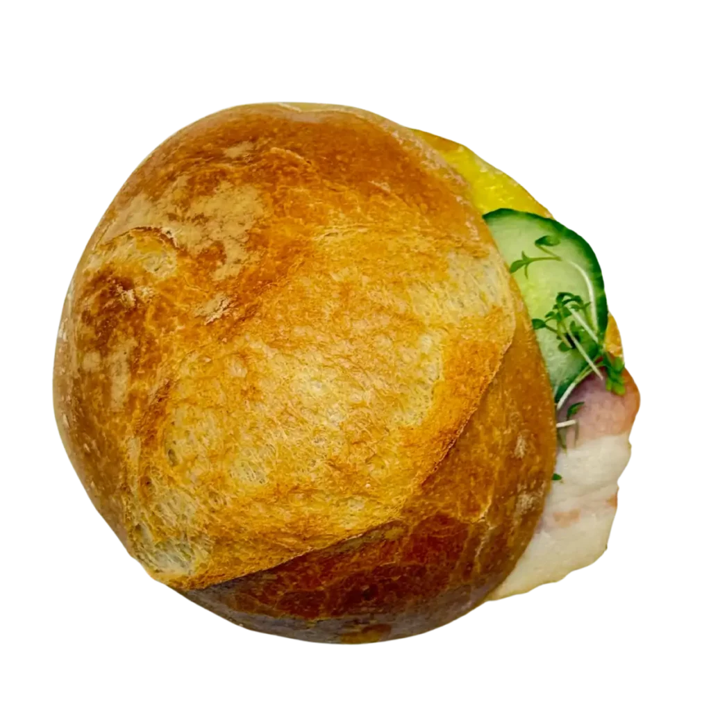 Ein rundes Brötchen aus der Naturbackstube der Bäckerei Wiesender in Pfaffenhofen, gefüllt mit Gurkenscheiben, Grünzeug und einem Stück Weißkäse oder Fleisch, auf weißem Hintergrund.