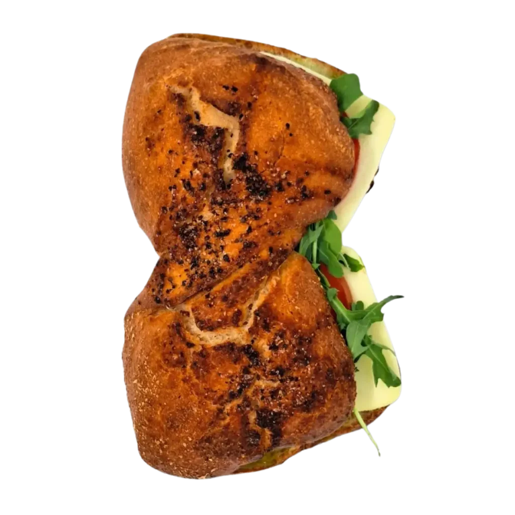 Ein getoastetes Sandwich der Bäckerei Wiesender in Moosburg aus dunklem, knusprigem Brot, gefüllt mit Blattgemüse, Tomatenscheiben und einer Käsescheibe, von oben gesehen auf weißem Hintergrund.