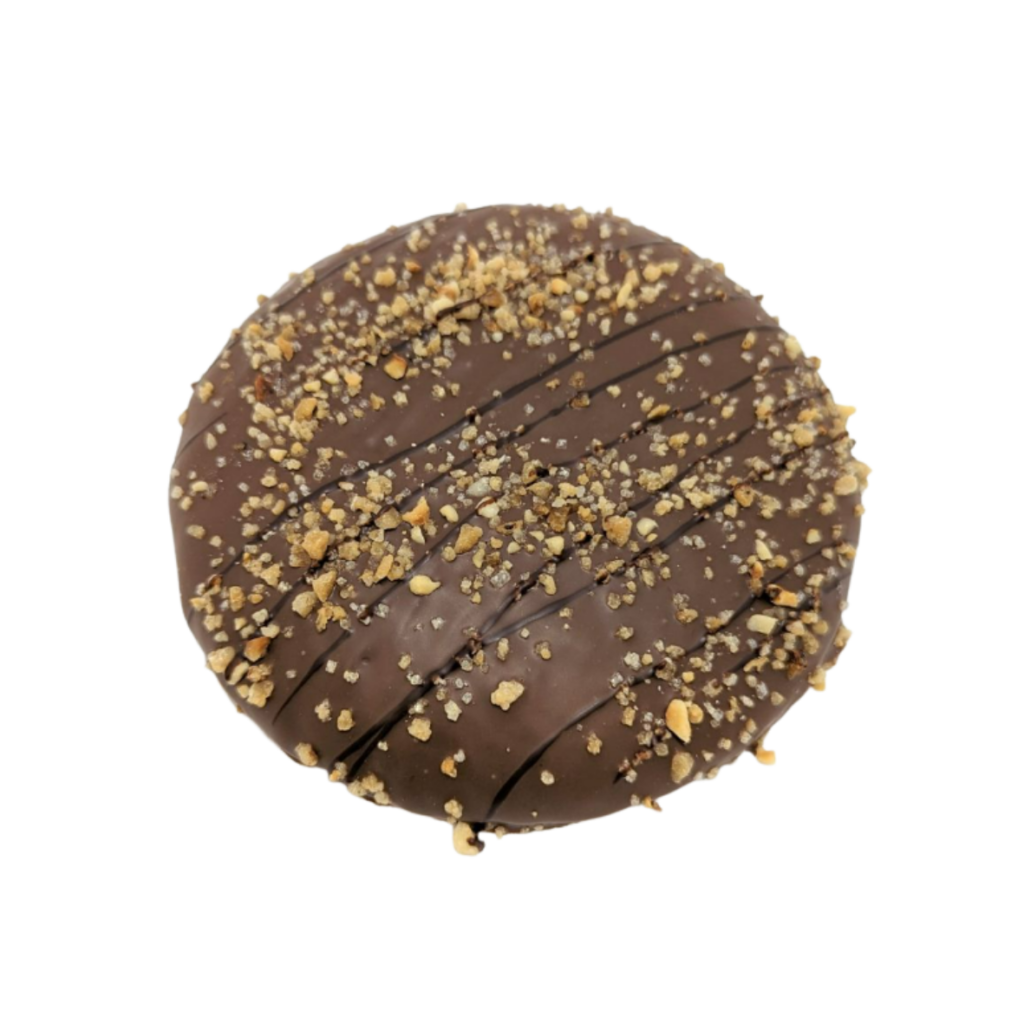 Ein runder, mit Vollmilch Schokolade überzogener Lebkuchen der Bäckerei Wiesender, der mit dunkler Schokolade beträufelt und mit gehackten Nüssen bestreut ist, vor einem weißen Hintergrund.
