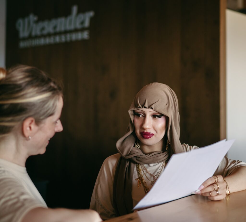 zwei Frauen stehen an einer Holztheke und sprechen über ein Dokument